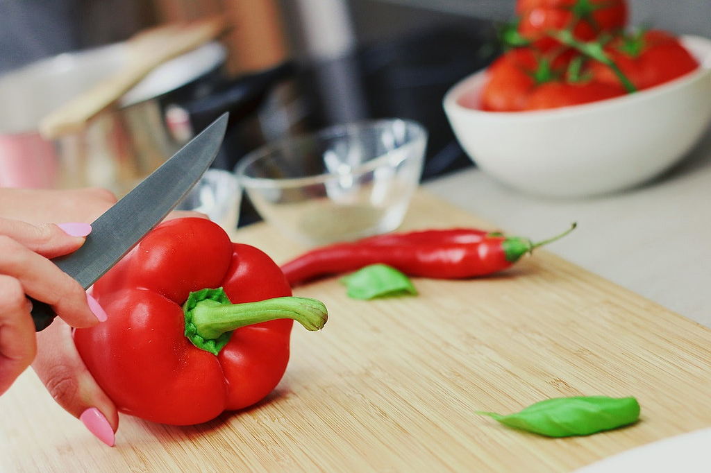 Best wood for cutting board: a hand slices a bell pepper on a cutting board