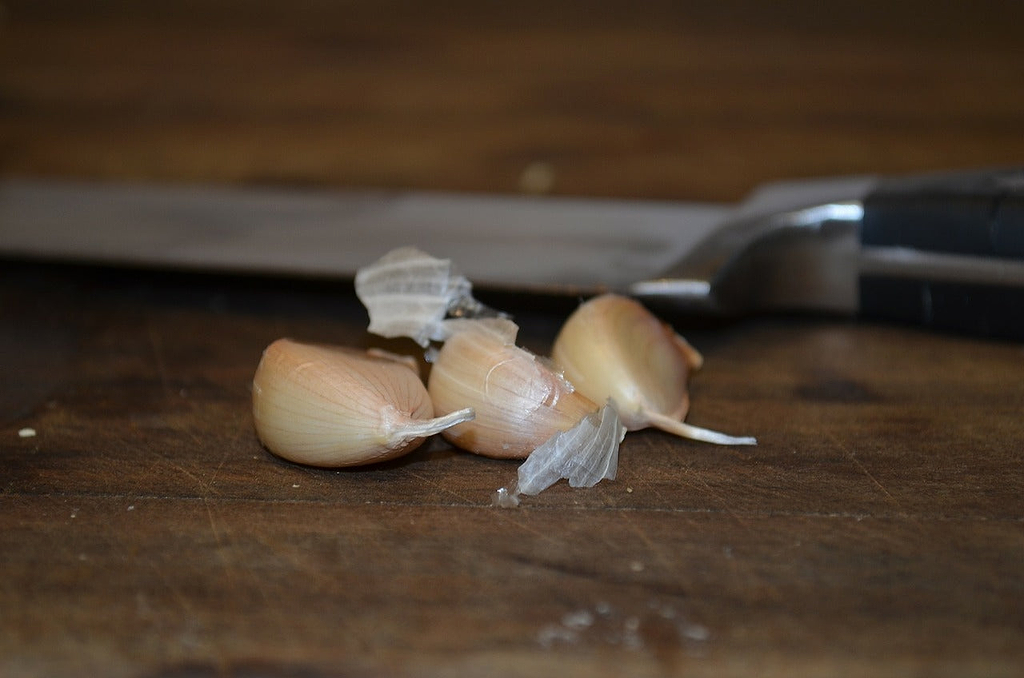 How to cut garlic: knife and garlic cloves on cutting board
