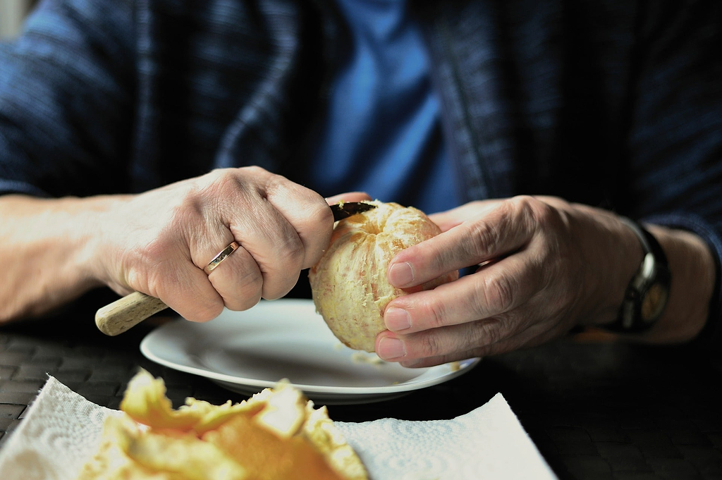 Paring knives: A man peels an orange with a paring knife