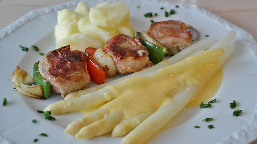 How to cut asparagus: whole white asparagus spears plated with grilled meat
