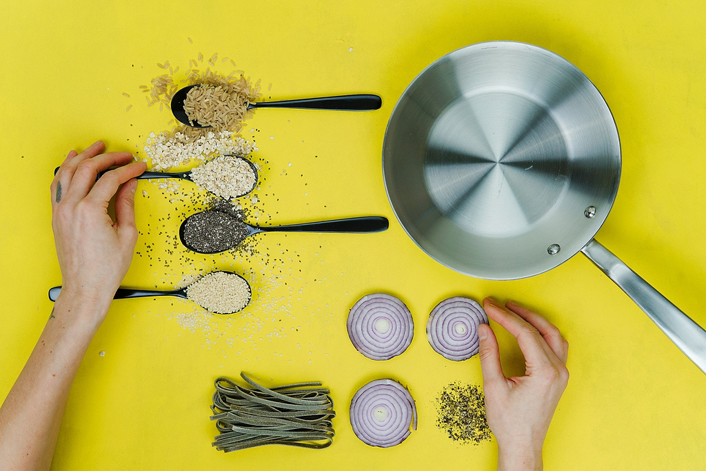 Cooking with stainless steel: ingredients artfully laid out next to a stainless steel pan