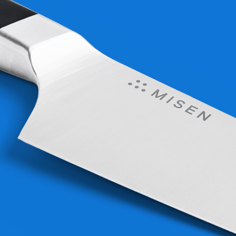 Misen chef's knife blade close-up showing bolster and laser-etched logo