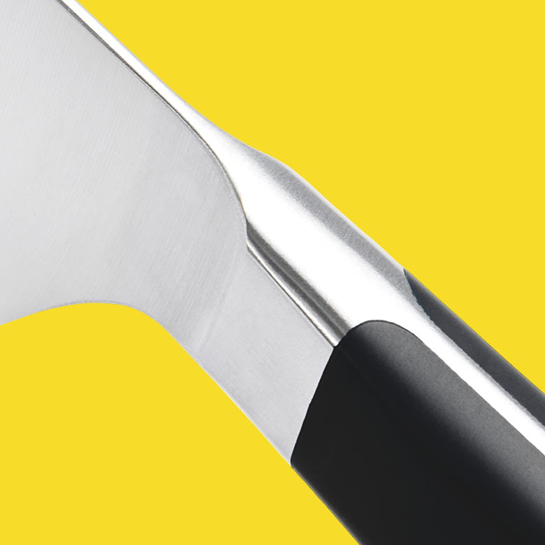 Close-up of stainless steel chef knife bolster and black handle
