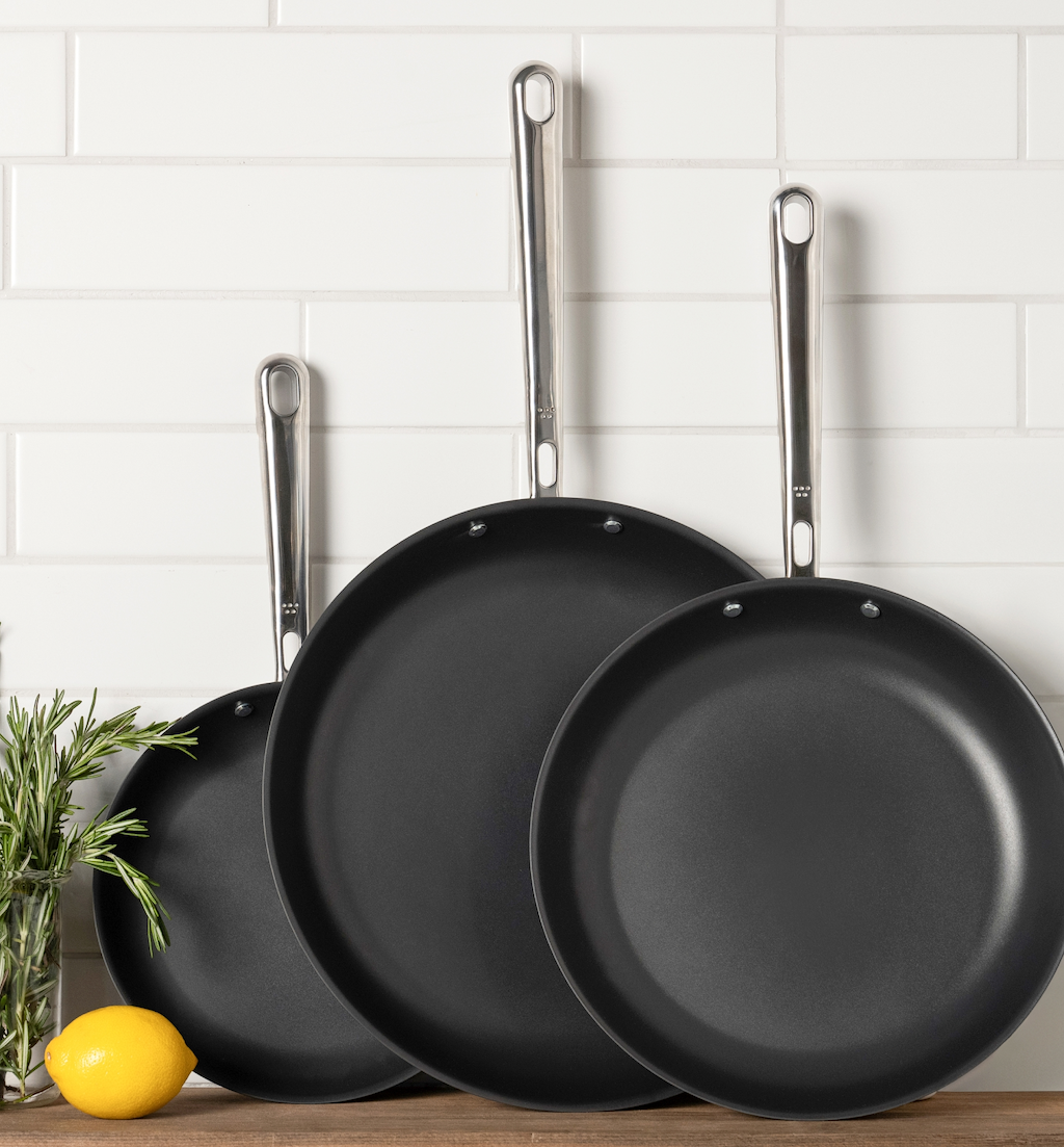 Three-piece nonstick frying pan set with stainless steel handles on kitchen counter