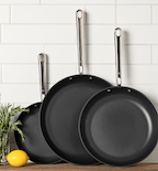 Three-piece nonstick frying pan set with stainless steel handles on kitchen counter