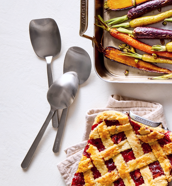 Misen stainless steel spatulas beside roasted rainbow carrots on a sheet pan and a lattice-top cherry pie