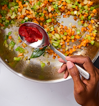 Adding tomato paste to sautéed mirepoix vegetables in a Misen stainless steel pan