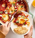 Shakshuka with feta cheese and fresh herbs served in a cast iron skillet
