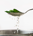 Fresh snap peas lifted from boiling water on a slotted spoon while blanching