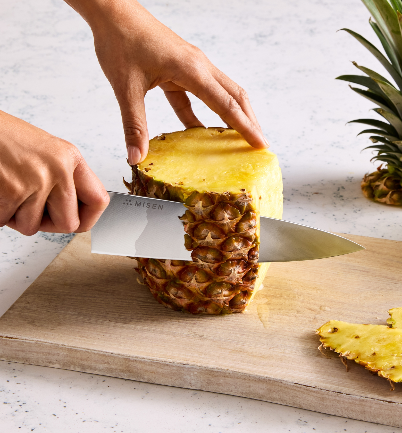 Misen chef's knife cutting pineapple skin on wooden cutting board