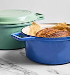Enameled cast iron Dutch ovens in blue and sage green with freshly baked sourdough bread