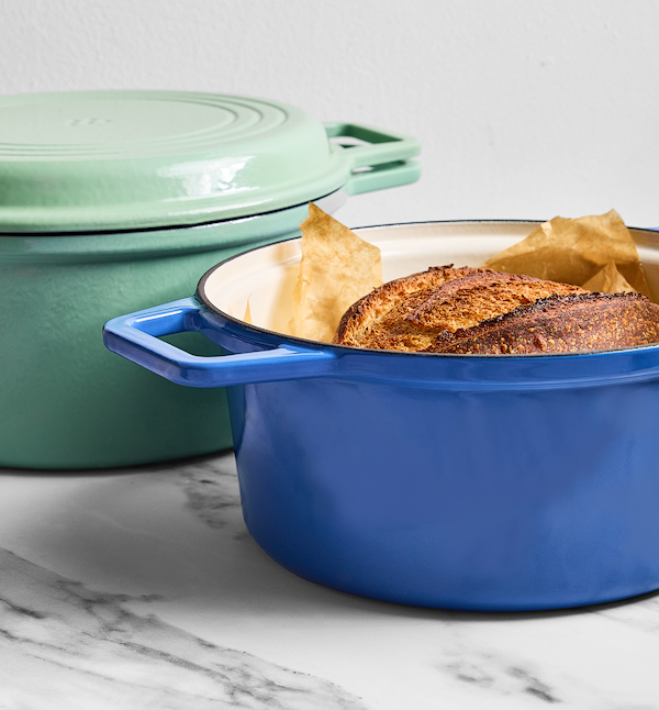 Enameled cast iron Dutch ovens in blue and sage green with freshly baked sourdough bread