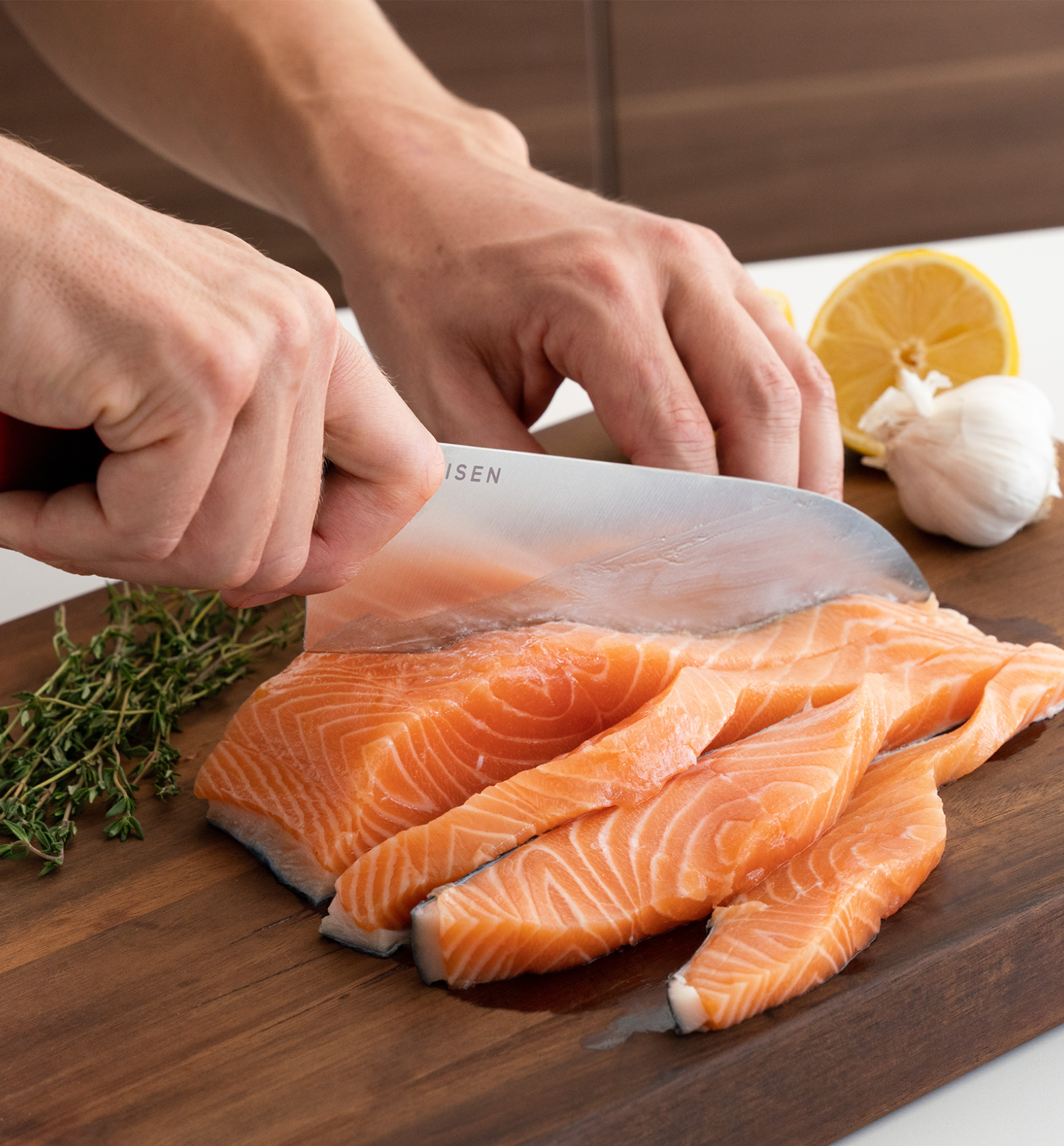 Chef slicing fresh salmon fillet on wooden cutting board with lemon and garlic