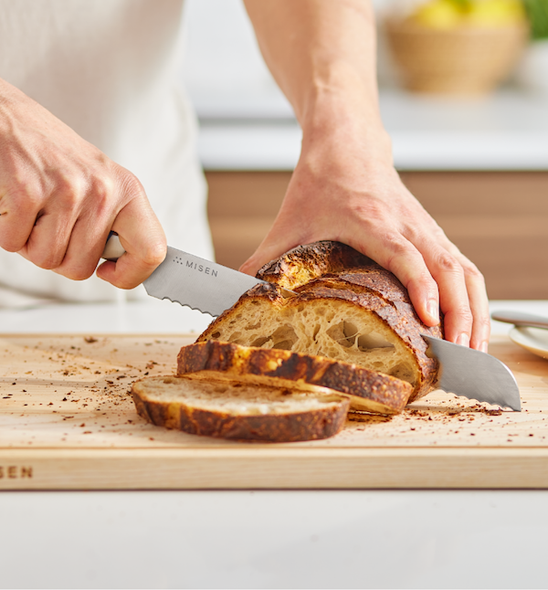 Misen bread knife slicing rustic sourdough loaf on wooden cutting board