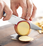 Misen paring knife slicing a fresh red apple on a wooden cutting board
