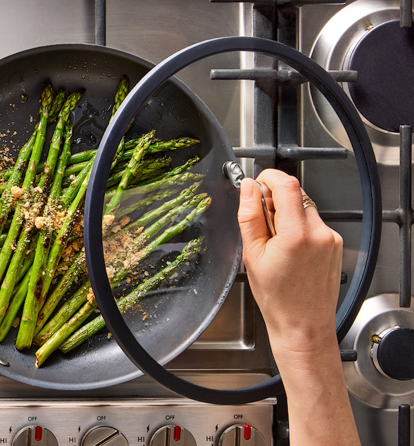 Sautéed asparagus with breadcrumbs cooking in a nonstick skillet on a gas stove