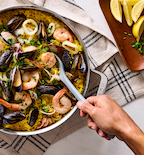 Seafood paella with mussels, shrimp, and squid in a stainless steel pan