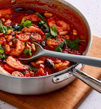Shrimp and white bean tomato stew with fresh herbs in stainless steel pan