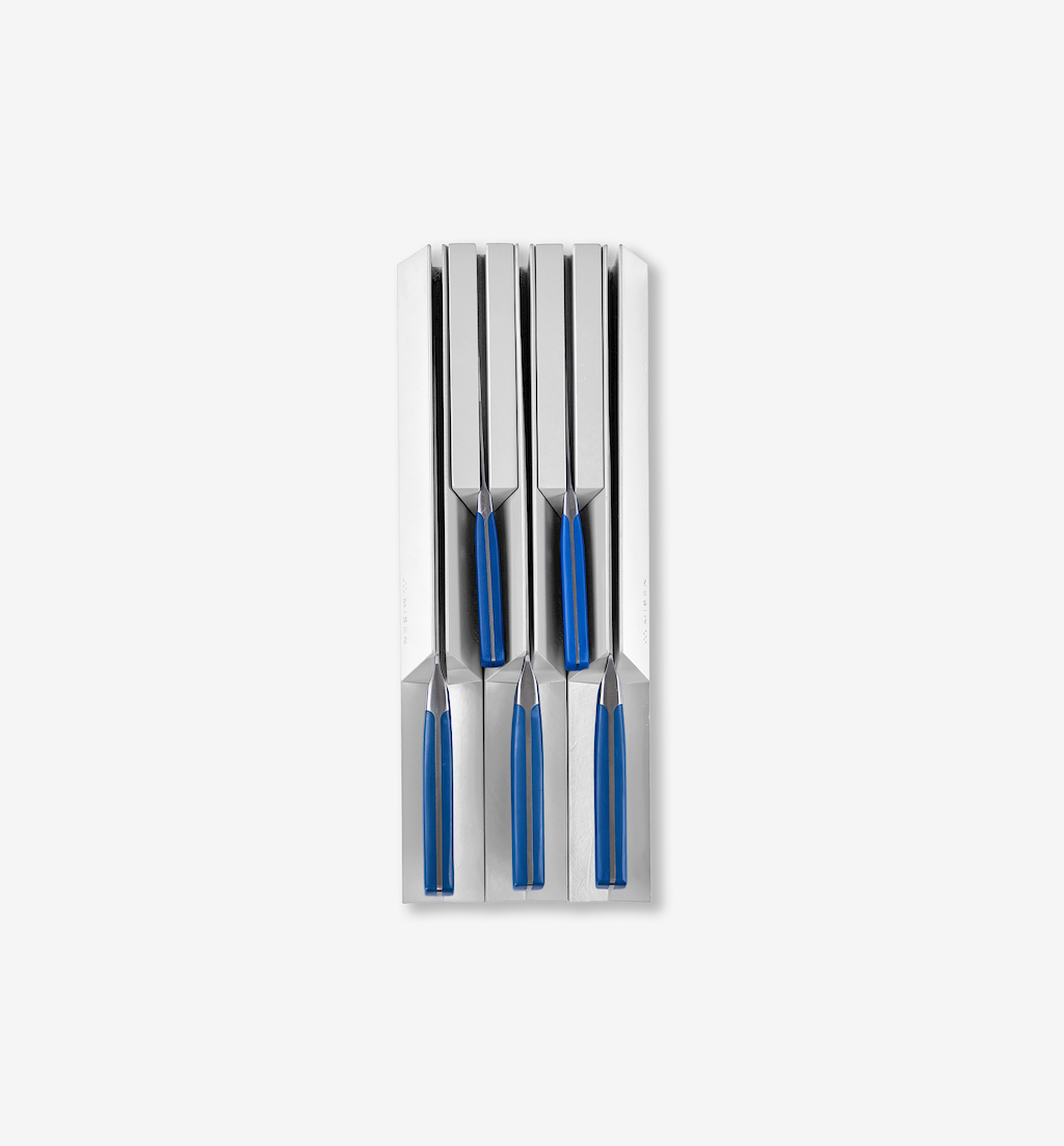 Set of four steak knives with blue handles stored in a stainless steel knife block drawer organizer
