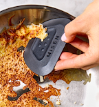Misen pan scraper removing stuck food from stainless steel skillet