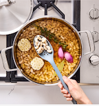 Cooking white beans with garlic, shallots, thyme, and bay leaf in a stainless steel pot on gas stove