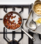 Toasted pecans in Misen stainless steel skillet with brown sugar and butter on gas stovetop