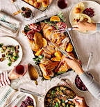 Thanksgiving turkey dinner spread with roasted brussels sprouts, cranberry sauce, and dinner rolls on holiday table