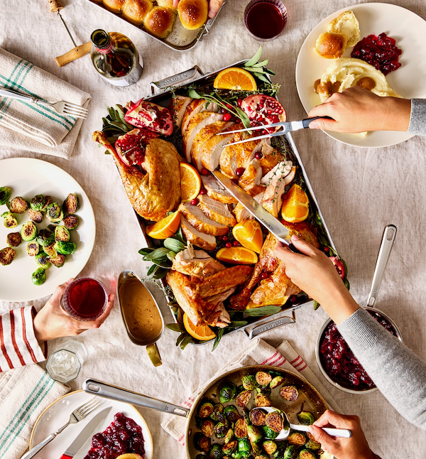Thanksgiving turkey dinner spread with roasted brussels sprouts, cranberry sauce, and dinner rolls on holiday table