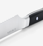 Misen steak knife with serrated blade and black handle close-up