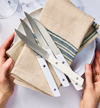 Misen steak knives with white handles displayed on linen napkins and white plate
