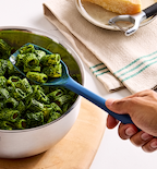 Rigatoni pasta tossed in vibrant green pesto sauce served in a stainless steel bowl