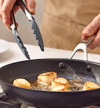 Searing sea scallops in a nonstick skillet with kitchen tongs