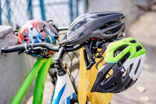 three bicycle helmets resting on the handlebars of bikes