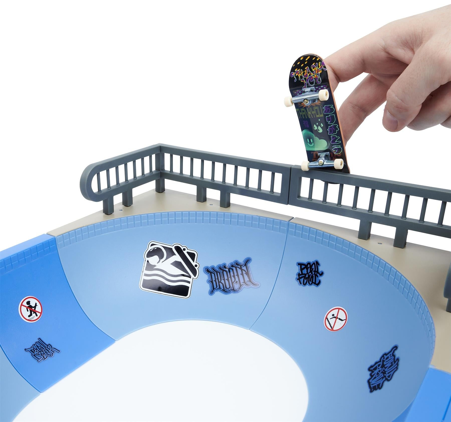 A hand holds the Tech Deck X-Connect Fingerboard Daewon Mega Bowl above a blue mini skate park ramp with railings and stickers—perfect for landing Daewon Song-inspired tricks.
