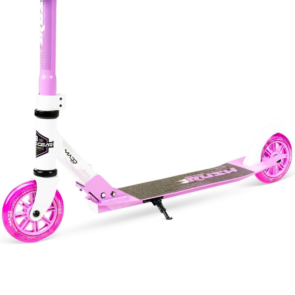 The Madd Gear (MGP) Metro Rush 125 Kids Foldable Scooter in white and purple features pink wheels, a black grip deck, adjustable handlebar, and kickstand, shown against a white background.