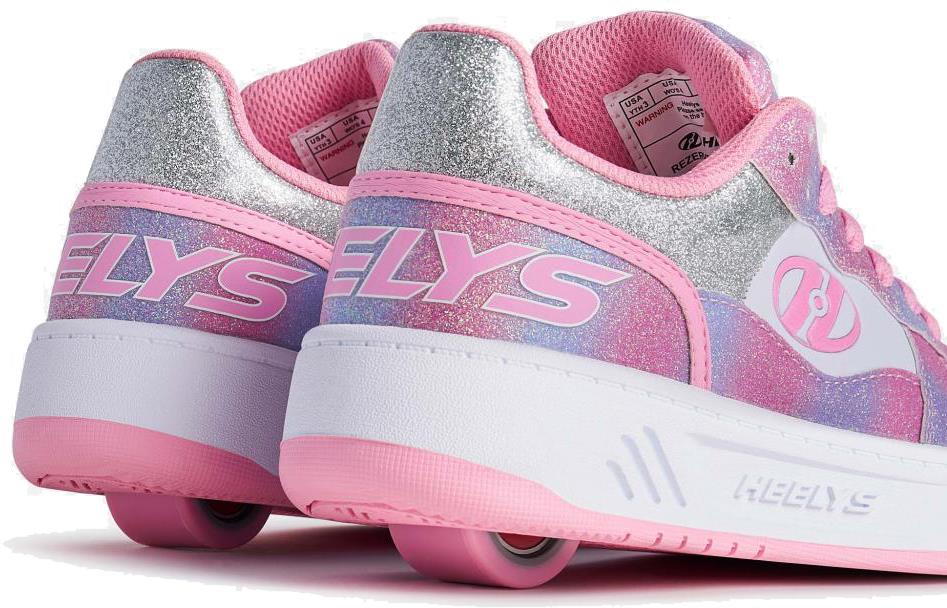 Close-up of two Heelys Rezerve Low Girls Shoes in light pink, white, and rainbow colors with glittery accents and visible heel wheels. The "Heelys" brand is on the sides—an ideal beginner-friendly choice.