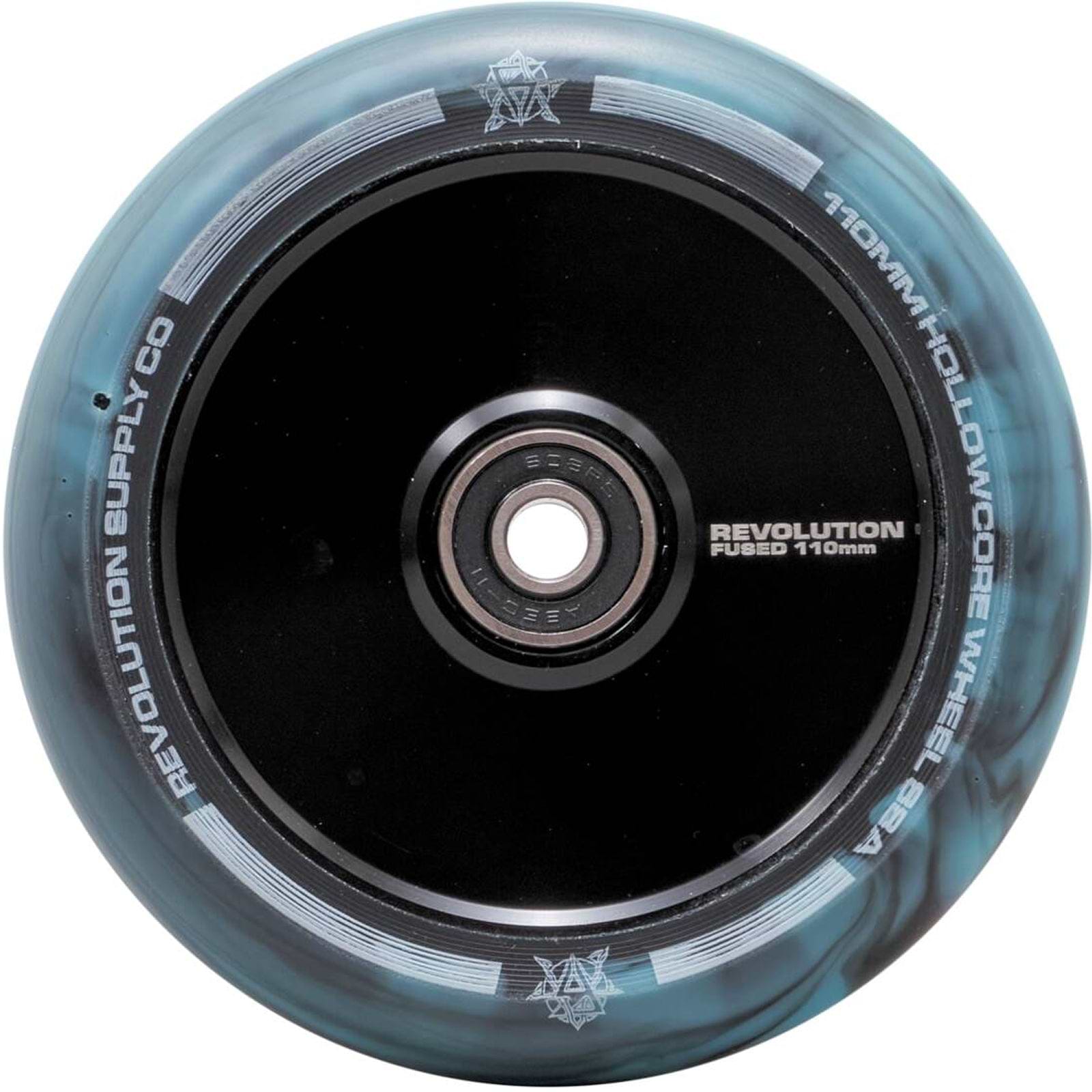 A close-up image of the Revolution Fused Core 110mm Stunt Scooter Wheel in Black/Blue by Revolution showcases their Fused Wheel Technology. The wheel features a sleek hollow-core design with a blue-gray outer rim, enhanced by multicolor effects and a visible bearing at the center.