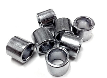 A scattered pile of seven Sushi Skateboard Bearing Spacers, made of shiny metal and cylindrical in shape, is displayed on a white background.