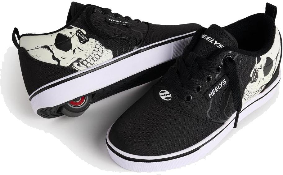 The Heelys Pro 20 PRNT Glow Boys Shoes in black/white feature glow-in-the-dark skull graphics, with one shoe displaying the low-profile wheel and the other showing off the bold skull design.