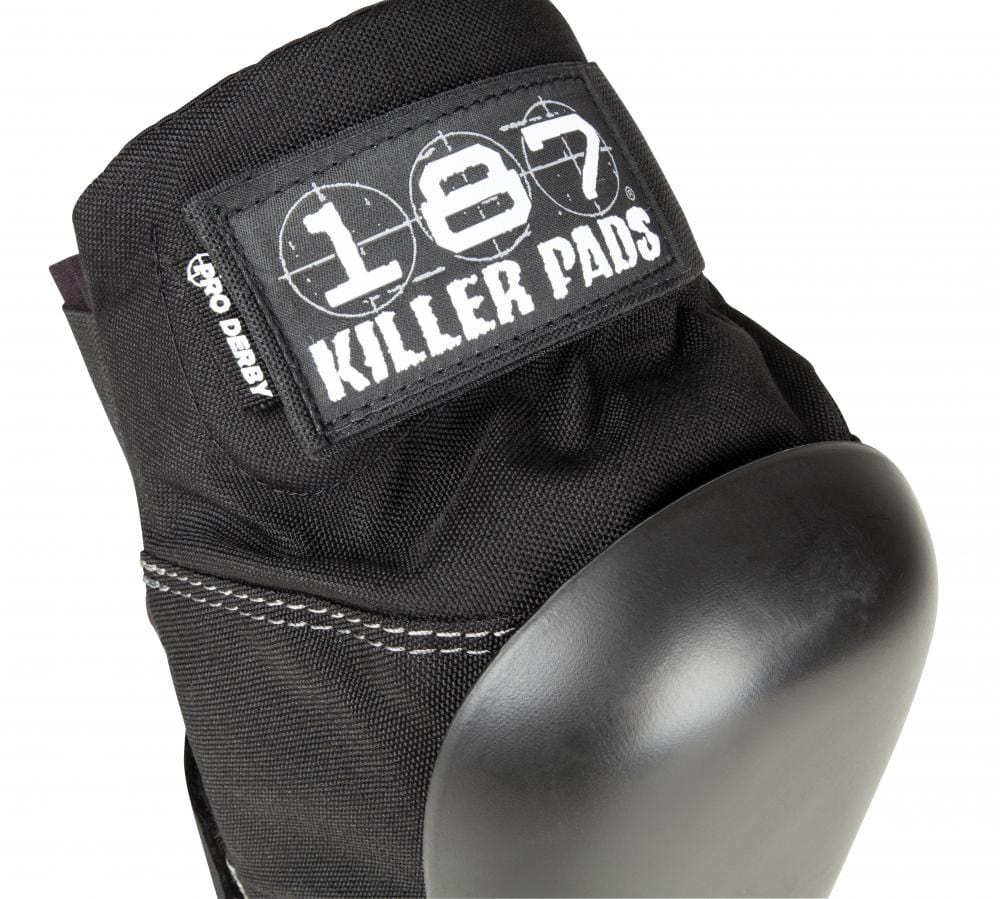Close-up of the 187 Killer Pro Derby Knee Protection Pads in black, featuring a hard protective cap ideal for action sports. The design includes the "187" logo and a "Pro Derby" label on the fabric above the cap. These pads also utilize V-22™ Dual Density Foam for enhanced comfort and security.