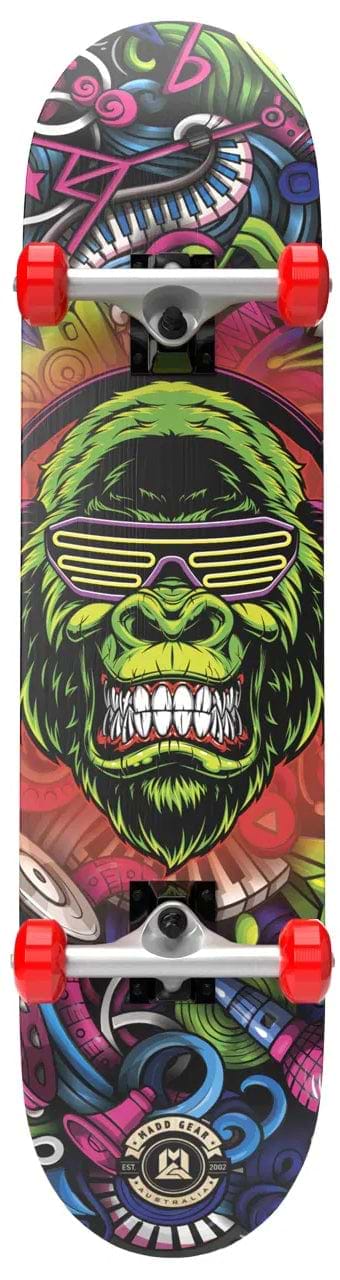 The Madd Gear MGP Pro Series BOOM'N LE Complete Skateboard (8" x 31") features red wheels and a colorful deck with graffiti-style art of a green gorilla in yellow glasses, surrounded by musical instruments and abstract designs.