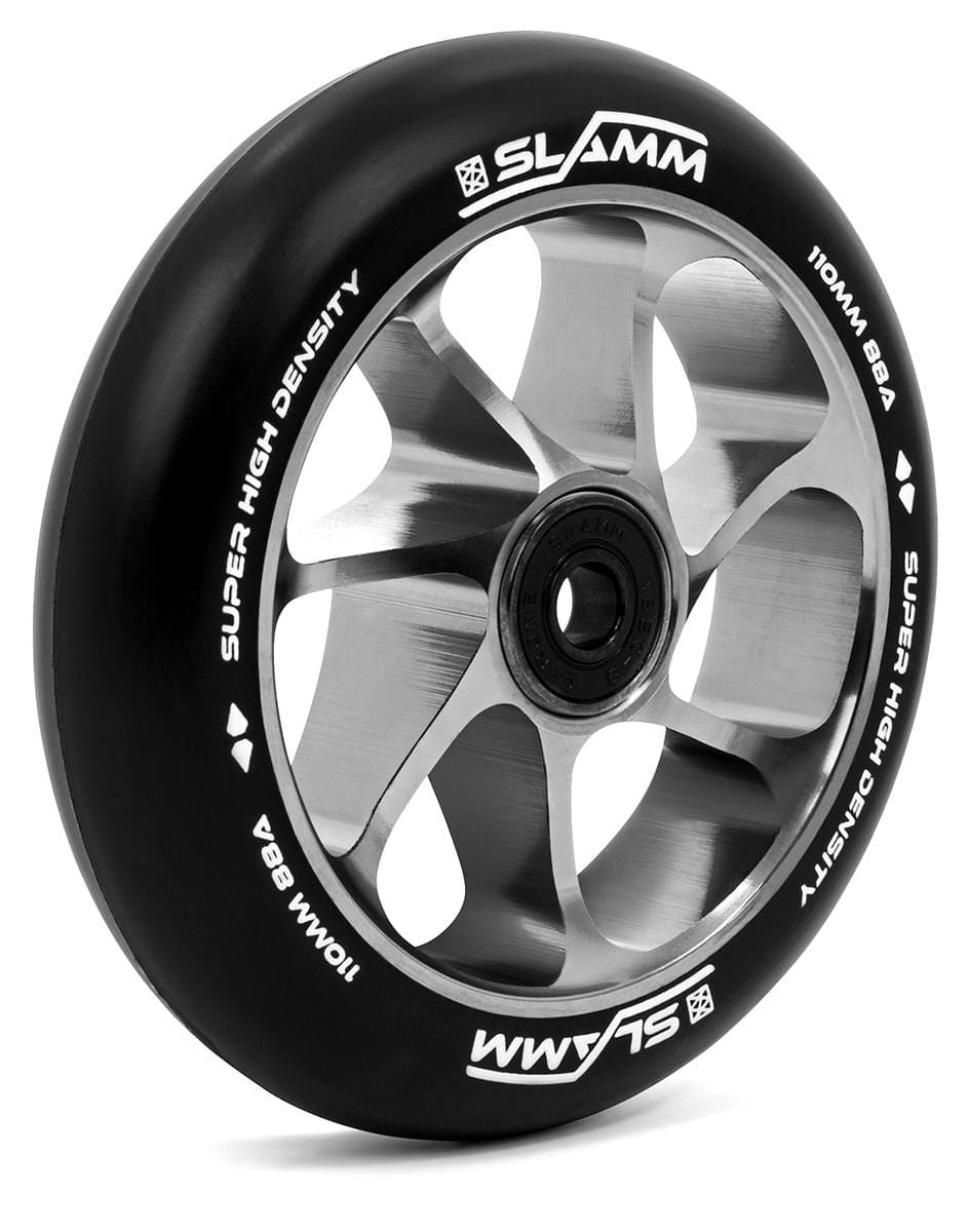 A close-up of the Slamm Team 110mm Stunt Scooter Wheel - Silver showcases a silver and black design, featuring white text on the tire that reads "Slamm," "Super High Density," and "110mm 88A." The aluminum core boosts durability, while the high-rebound PU construction guarantees smooth rides. This 110mm wheel includes a central bearing for effortless rotation.