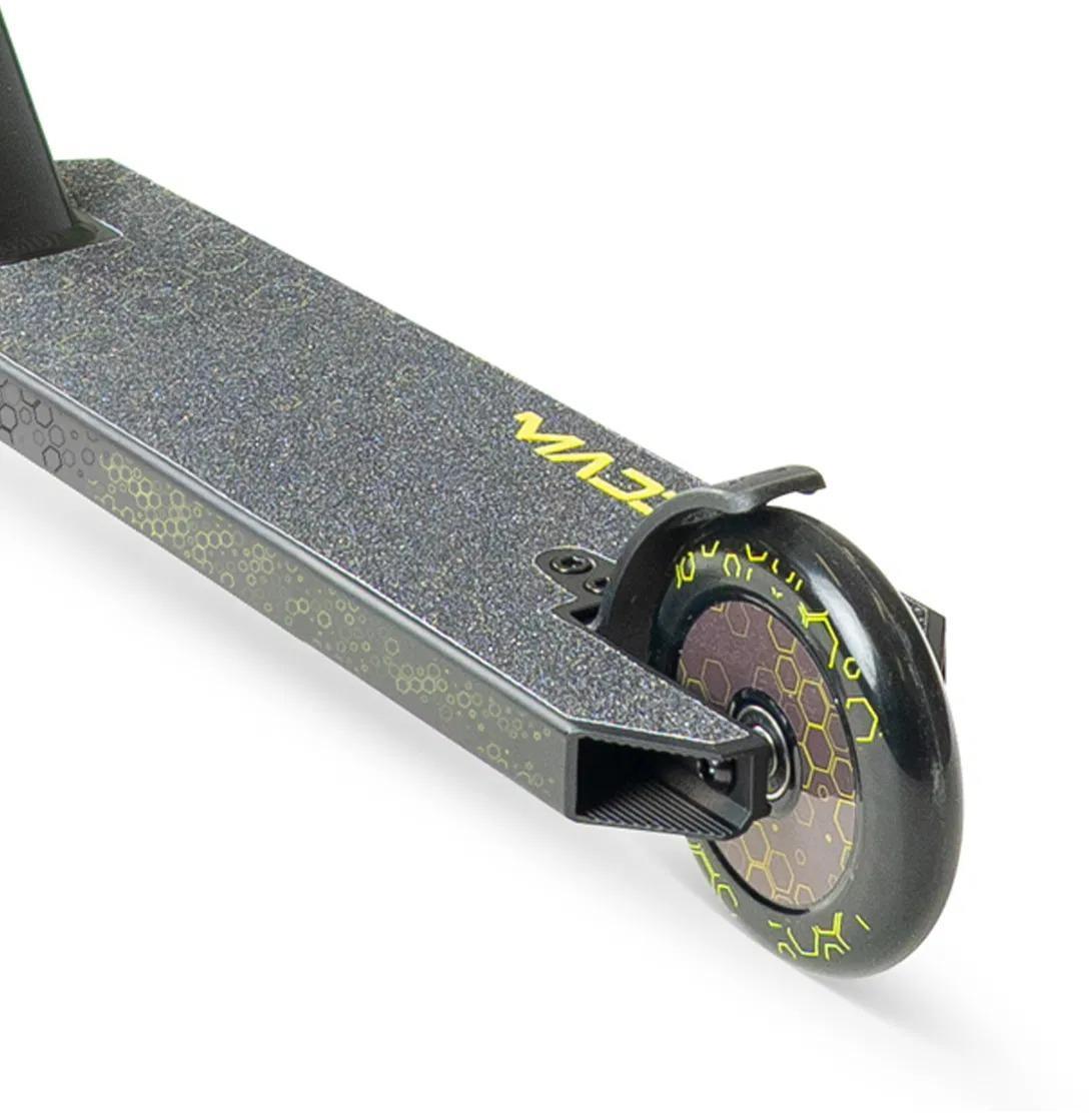 Close-up of the Madd Gear Viral Rave Complete Stunt Scooter - Neon deck, showing its textured grip with a yellow honeycomb pattern and a black rear wheel with matching honeycomb design.