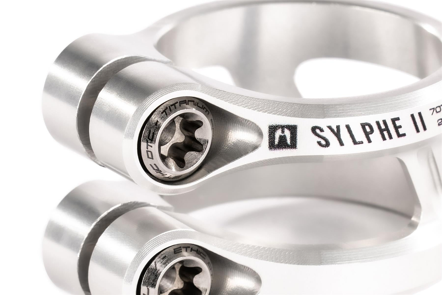 Close-up of two Ethic DTC Sylphe V2 2 Bolt Oversized Stunt Scooter Clamps in Raw, highlighting detailed bolts and smooth silver finish with engraved text—ideal lightweight clamp for stunt riders from Ethic.