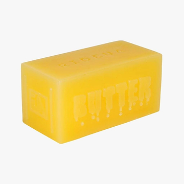 A rectangular yellow soap, reminiscent of a stick of butter with "BUTTER" engraved on its side, is the UrbanArtt Butter Block Wax. It features a matte finish and rounded edges for smooth performance, presented in a sleek design against a plain white background.