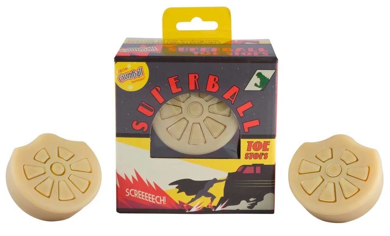 Two natural Gumball Superball Roller Skate Long 30mm Toe Stops sit beside a box labeled "Superball Toe Stops" by Gumball, featuring retro comic-style art with bold text and a screeching car. Perfect for roller derby skaters.