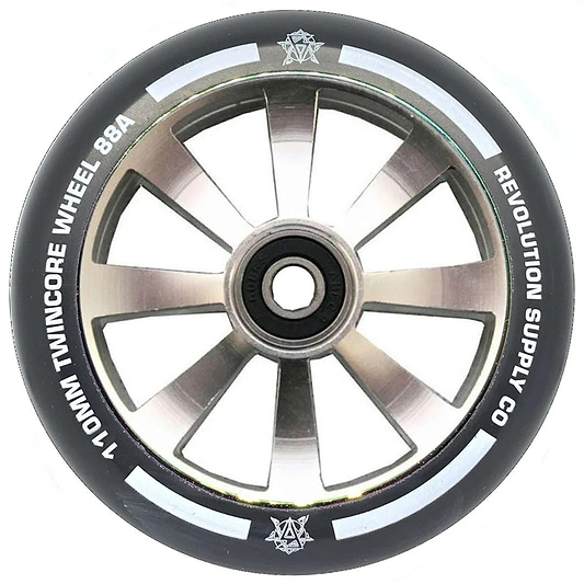 A close-up of the Revolution Twin Core 110mm Stunt Scooter Wheel - Raw shows its black and silver design, eight spokes, white "110MM TWINCORE WHEEL 88A" and "REVOLUTION SUPPLY CO." text, and a central ABEC 9 bearing for top performance.
