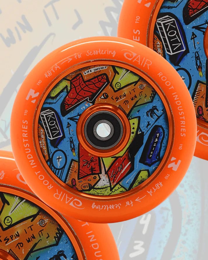 Close-up of three Root Industries x KOTA Limited Edition AIR 110mm Stunt Scooter Wheels in orange, each featuring colorful abstract designs with shapes, numbers, and text on the inner circle.