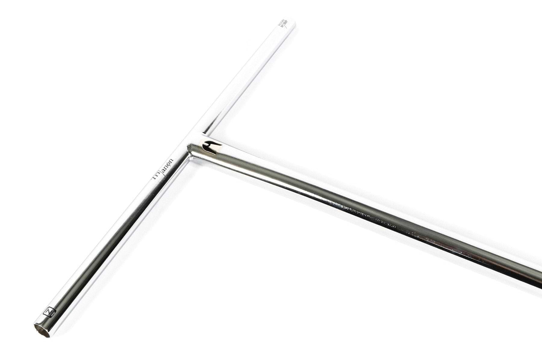 This is a T-shaped metal tool made from chromoly steel featuring shiny, smooth surfaces. The longer vertical bar forms a classic T, similar to the Ethic DTC Trianon Steel Standard ICS/IHC Stunt Scooter Bars in raw silver with dimensions of 670mm x 560mm. The image showcases its angled sections and polished finish.