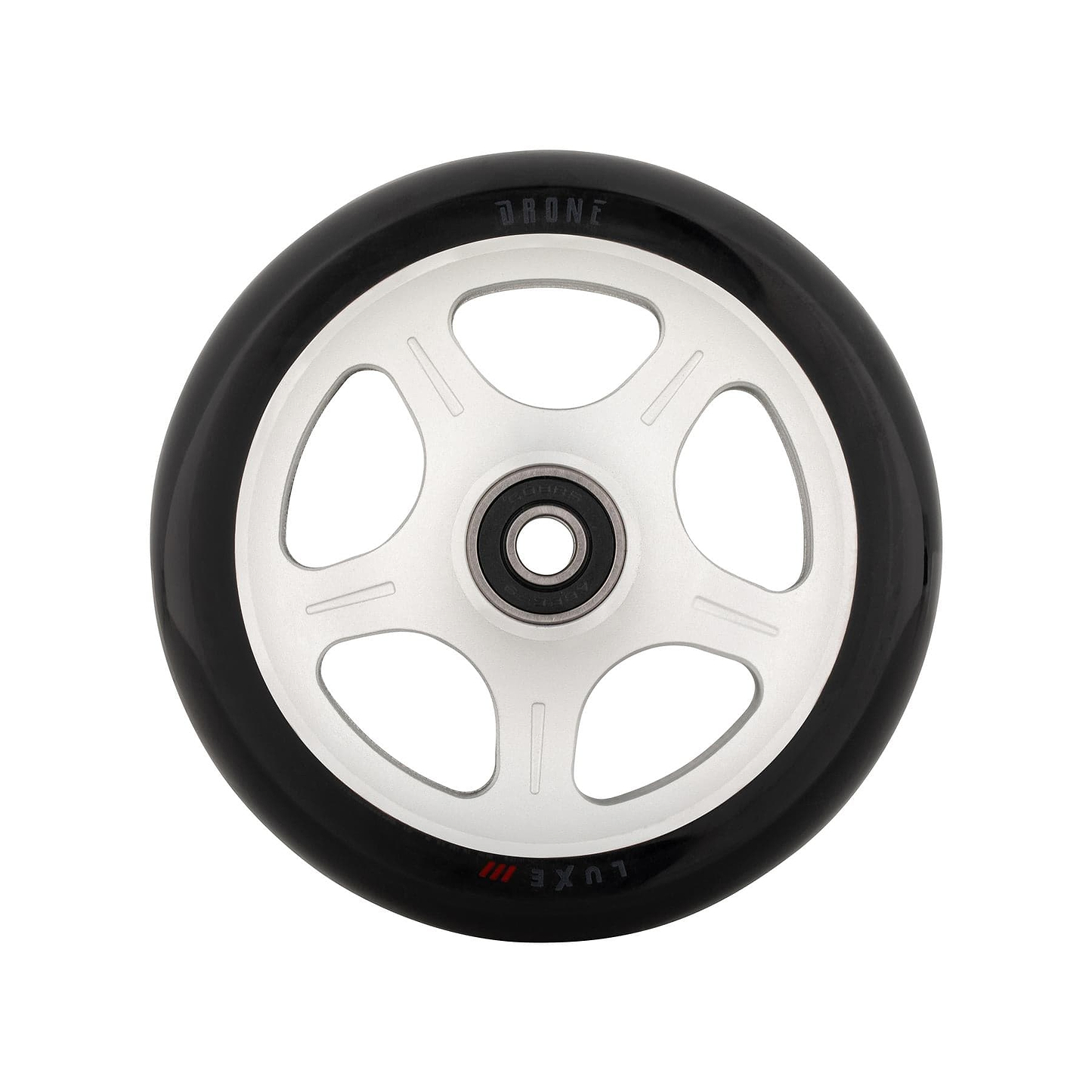 A close-up of a Drone Luxe 3 Dual-Core 110mm stunt scooter wheel reveals a black tire with a white, star-patterned core featuring five circular cutouts. "DRONE" and "Luxe" are engraved on the rim. The wheel is perfectly centered against a pristine white background.